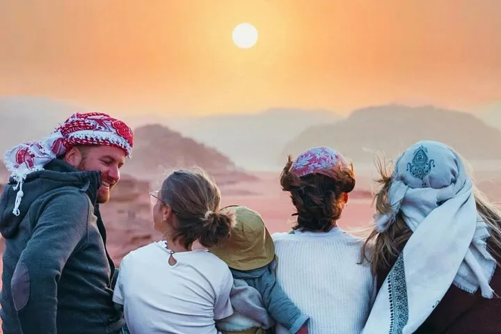 A 4x4 jeep below sandstone cliffs on a Wadi Rum desert tour with an overnight in a Bedouin camp
