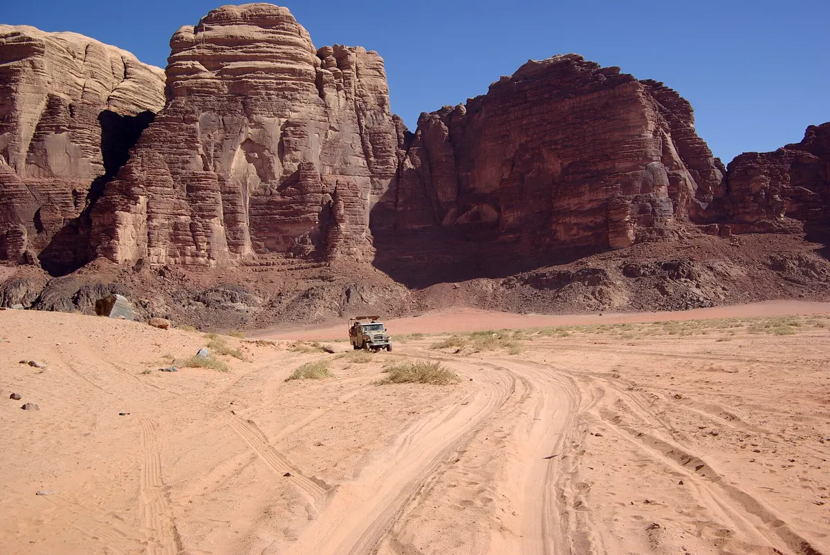 A 4x4 below the cliffs near Lawrence Spring on a Wadi Rum cave camping tour